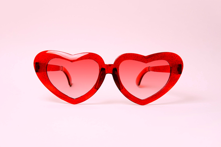 A pair of red heart shaped sun glasses on pink background.の写真素材