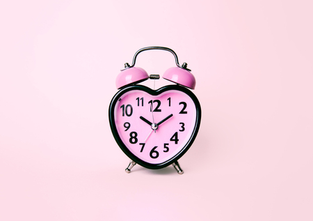 Heart shaped clock on pink background. Valentines day and love and duration concept.の写真素材