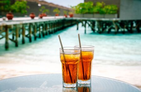 Iced tea against tropical Overwater Bungalow Resort on the beachの写真素材