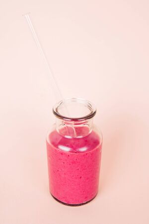 Minimalist composition of glass with raspberry smoothie and with reusable glass straw on pink backgroundの写真素材