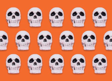 Skull pattern on orange background. Creative Halloween concept.の写真素材