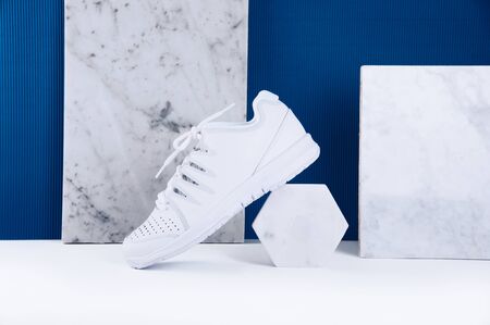 Pair of white sneakers on trendy blue background. Healthy lifestyle concept.の写真素材