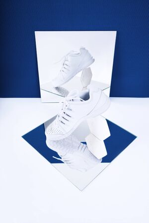 Pair of white sneakers on trendy blue background. Healthy lifestyle concept.の写真素材