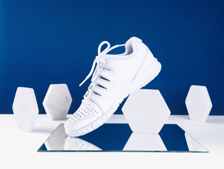 Pair of white sneakers on trendy blue background. Healthy lifestyle concept.の写真素材