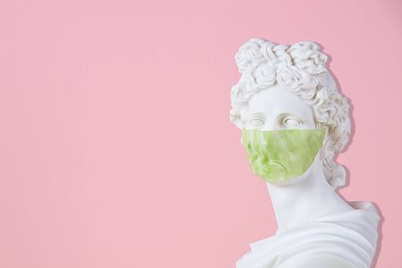 Gypsum statue with antiviral mask for protection against coronavirus, place for text.の写真素材