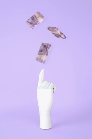 Gloved hand playing with levitating soap bars. Cleaning Hands Concept.の写真素材