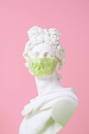 Gypsum statue with antiviral mask for protection against coronavirus, place for text.の写真素材