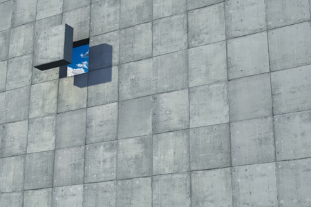 Hole in a concrete wall makes a peek to the a blue sky with white cloudsの写真素材