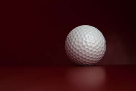 White golf ball lying on red leather greenの写真素材