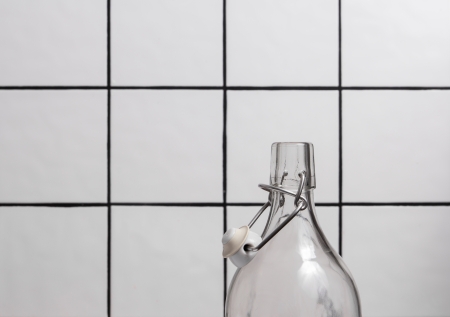 Glass bottle with flip top in front of a tile backgroundの写真素材