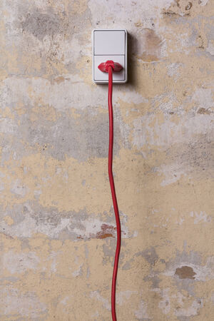 Red chord and plug in a white electrical socket