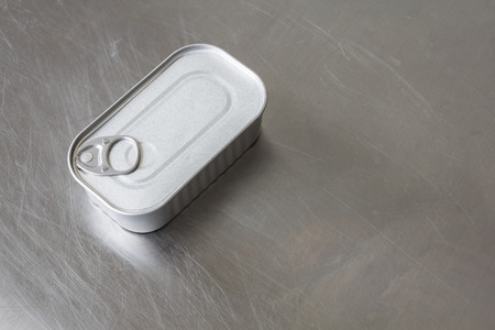 Square tin can standing on a scratched aluminum surfaceの写真素材