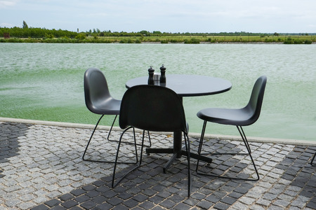 Black cafe furnitures standing outside, by the waterfront