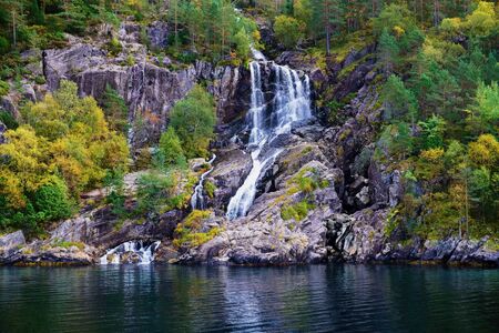 small and idyllic waterfall in the tree covered mountains surrounding Lysefjord in Norwayの写真素材