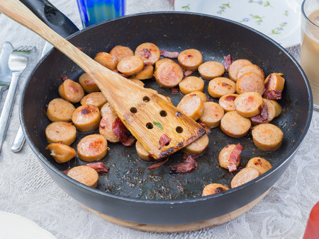 Kitchen pan with cooked sausage and baconの写真素材