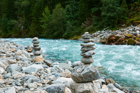 Small rocks stacked by the gushing river floating from Folgefonna glacier through Buerdalen in Norwayの写真素材