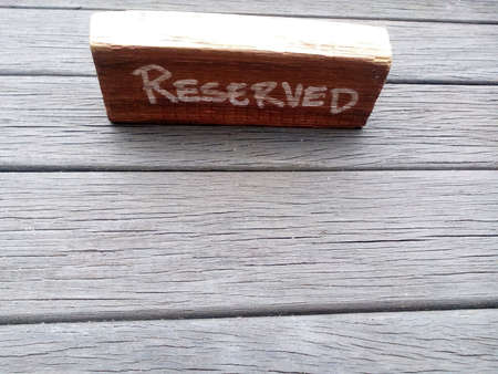 Reserved sign written on a wooden block on a wooden table top