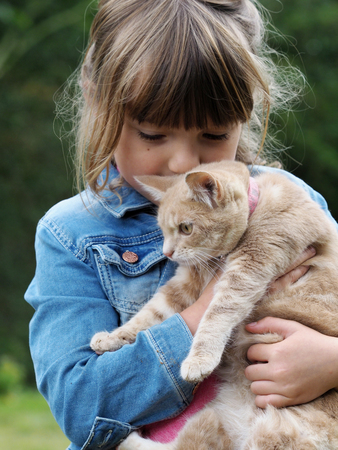 A cute young girl cuddles her pet cat.の写真素材