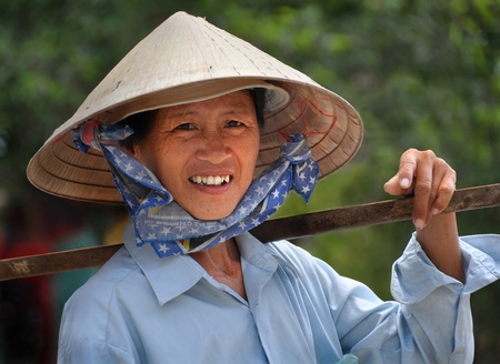 Ho Chi Minh City, Vietnam - April 15, 2009: A woman in a traditional Vietnamese hat takes a break from selling fruit and vegetables.のeditorial素材