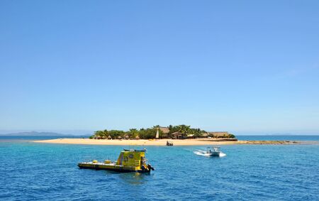 South Sea Island, Fiji - October 01, 2012: A boat comes to ferry tourists to the island for a day of snorkeling, entertainment and underwater viewing of the reef via the submarine in the foreground.のeditorial素材