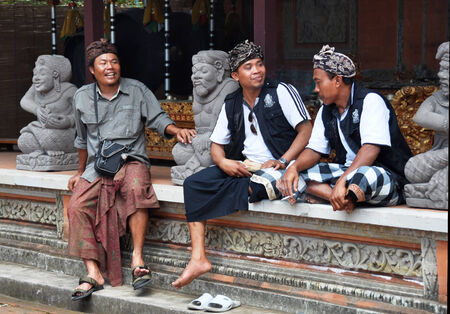 Bali, Indonesia - October 07, 2011: Balinese men talking in a Hindu temple in Celuk. They are wearing traditional religious black and white fabric which symbolises good and evil. They are also wearing traditional Balinese cloth hats called Destar.のeditorial素材