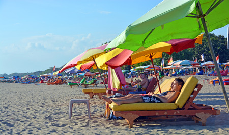 Bali, Indonesia - September13, 2015: Tourists Snooze on colourful recliner chairs at Legian Beach in the afternoon.のeditorial素材