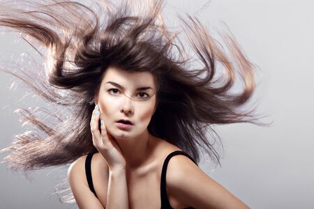 fashion woman with flying hair on a gray background の写真素材
