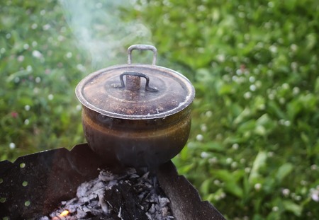 Old pan on stove outdoors in process of herbal tea preparation.の写真素材