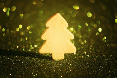 Small decorative wooden christmas tree on sparkling glitter backgroundの写真素材