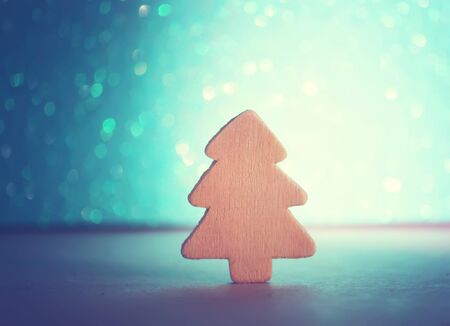 Small decorative wooden christmas tree on sparkling glitter backgroundの写真素材