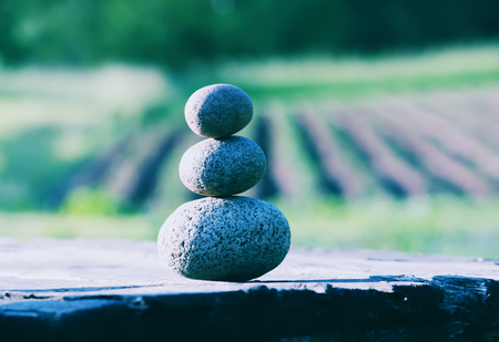 Pyramide of three oval stones on a wooden table outdoorsの写真素材