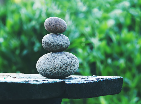 Pyramide of three oval stones on a wooden table outdoorsの写真素材