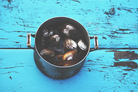 Mussels in an old pan on a wooden table outdoors