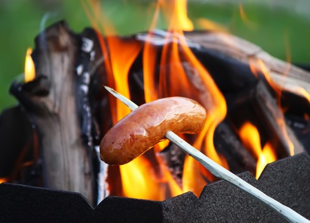 Sausages grilling for a picnic outdoors over the brazierの写真素材