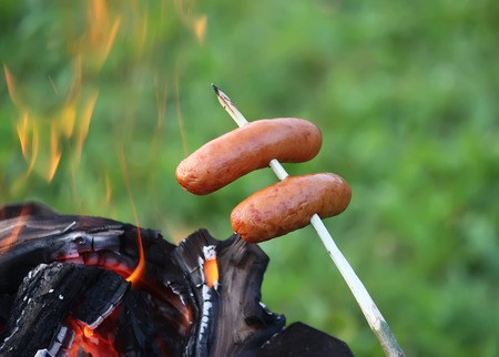 Sausages grilling for a picnic outdoors over the brazierの写真素材