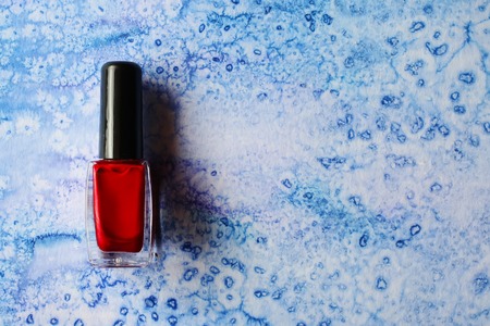 Red nail polish bottle on watercolor backgroundの写真素材
