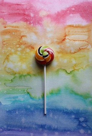 Sweet colorful lollipop on colorful decorative watercolor paper background.の写真素材