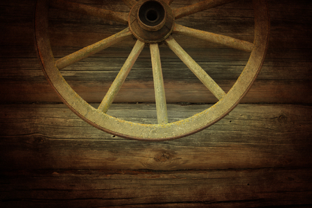 Old wooden wheel on the wooden wallの写真素材
