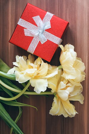 Yellow tulip flowers with red gift box on the table.の写真素材