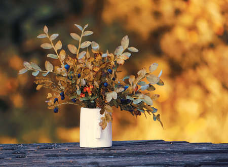 Bouquet of ripe wild forest blueberry and cranberry plants in the wooden vase.の写真素材