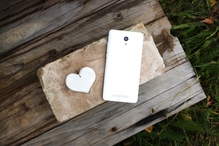 White smart phone and handmade heart on the brickの写真素材