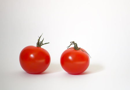 Two ripe red small tomatoes on a white backgroundの写真素材