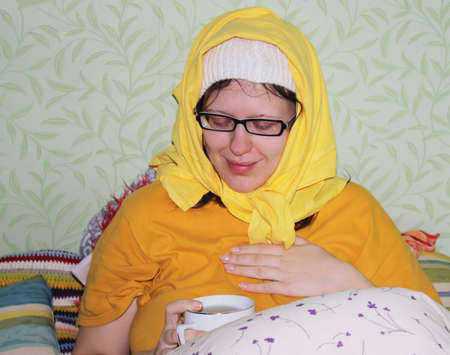 Young woman ill by seasonal influenza drinking hot tea.の写真素材