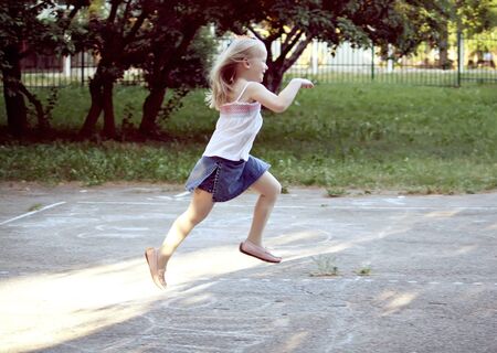 Adorable blonde girl dressed in a pettiskirt playing and running in a summer park in the countryside.の写真素材