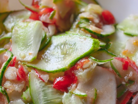 Salad of fresh vegetables. Cucumbers, tomatoes and green broad beans in a white plate on aged table background.の写真素材
