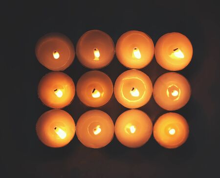 12 burning candles on dark background.の写真素材