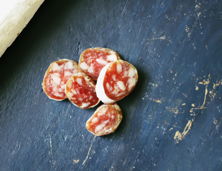 Dry cured sausage with spices on dark scratched aged wooden background.の写真素材