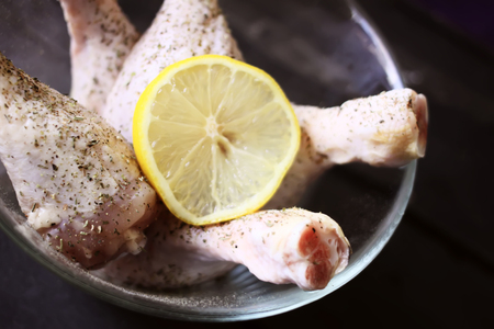 Raw chicken legs with herbs and lemon slice prepared for cooking.の写真素材