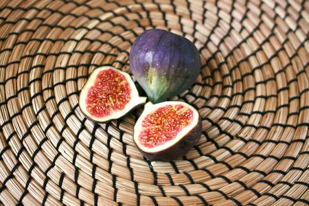 Whole fresh ripe sweet figs on wicker placemat background.の写真素材