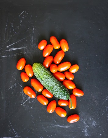 Fresh ripe tomatoes and cucumber on dark rustic background.の写真素材